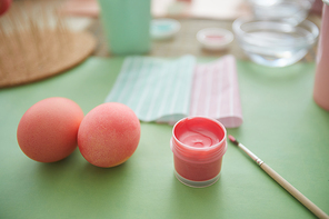 Close up of beautiful pastel pink eggs on table in art studio next to paint brush, Ester decorations concept, copy space