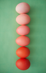 Above view background of painted Easter eggs in row gradient from red to pastel pink, copy space