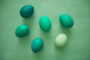 Above view of emerald Easter eggs arranged in minimal composition on green background, copy space