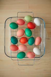 Above view background of red and green hand-painted Easter eggs on drying rack over wooden table in art studio, copy space