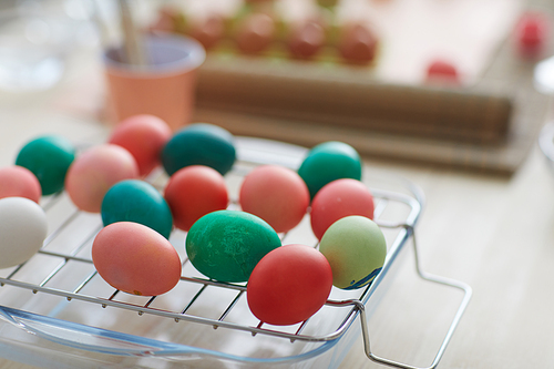 Close up background image of red and green hand-painted Easter eggs on drying rack in art studio, copy space