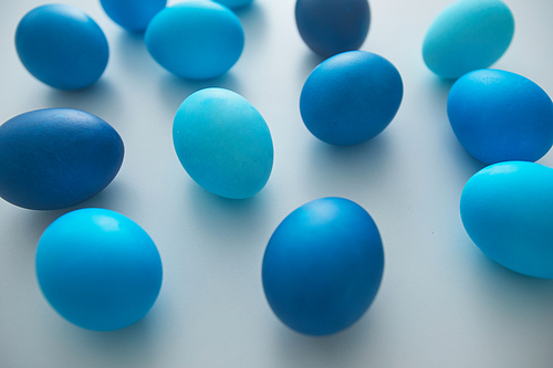 Close up view of hand-painted blue Easter eggs arranged in minimal composition on white background, copy space