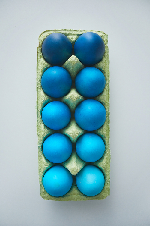 Above view of beautiful blue Easter eggs in crate arranged in minimal composition on white background, copy space