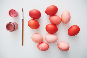 Top view of pastel pink Easter eggs arranged in minimal composition with paint brush on white background, copy space