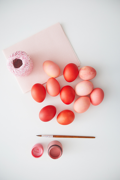 Above view of pastel pink Easter eggs arranged in minimal composition with paint brush on white background, copy space