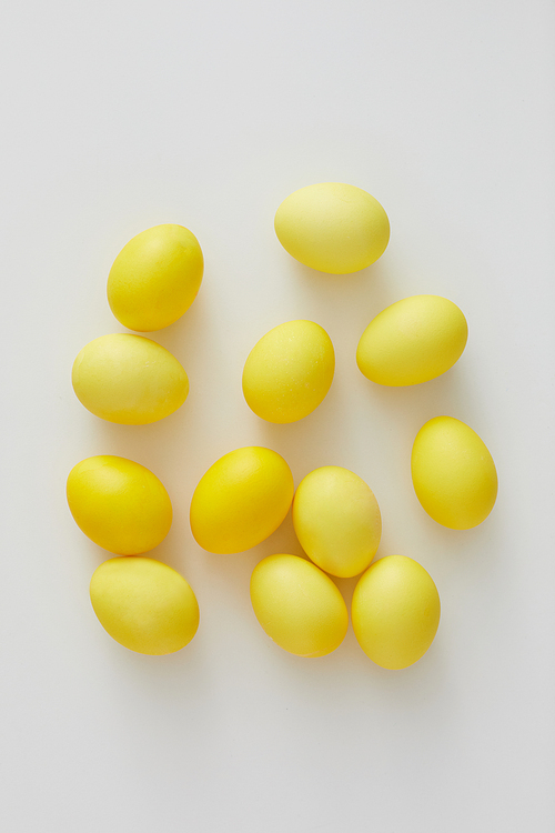 Top view of pastel yellow Easter eggs arraigned in minimal composition on white background, copy space