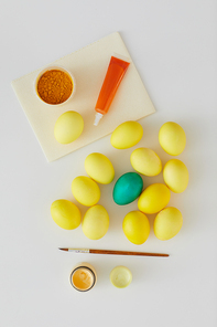 Above view of natural colored Easter eggs with green accent and paint brush arraigned in minimal composition on white background, copy space