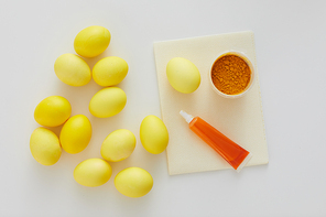 Above view of pastel yellow Easter eggs with natural color dye arraigned in minimal composition on white background, copy space
