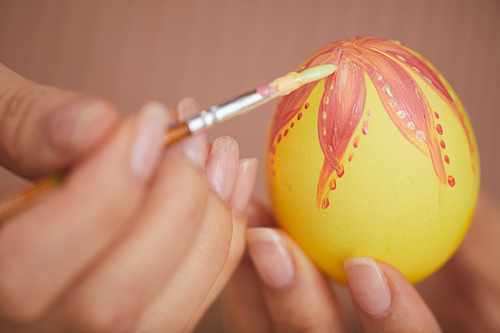 Extreme closeup of unrecognizable young woman painting intricate design on Easter egg, copy space