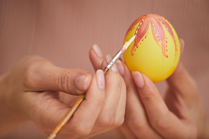 Extreme close up of female hands painting intricate design on Easter egg, copy space