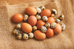 Backgroiund image of farmers chicken eggs and quail eggs in burlap wrapping, copy space
