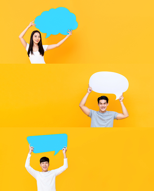 Group of happy smiling Asian men and woman holding speech bubbles with empty spaces for text on isolated yellow studio background