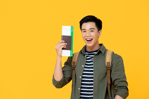 Young handsome Asian tourist man smiling and holding passport with boarding pass ready yo fly