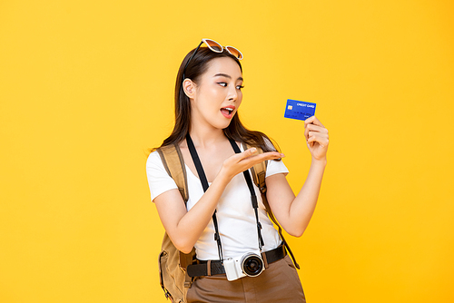 Asian woman tourist showing credit card isolated on yellow background