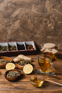 Tea, lemon and jar with hone on wooden surface on textured stone background
