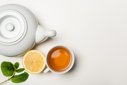 Top view of cup of tea, lemon and mint on white background with copy space