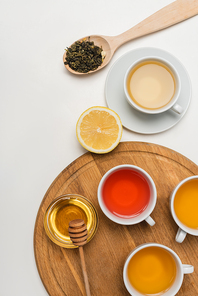 Top view of cups of tea near honey and lemon on white background