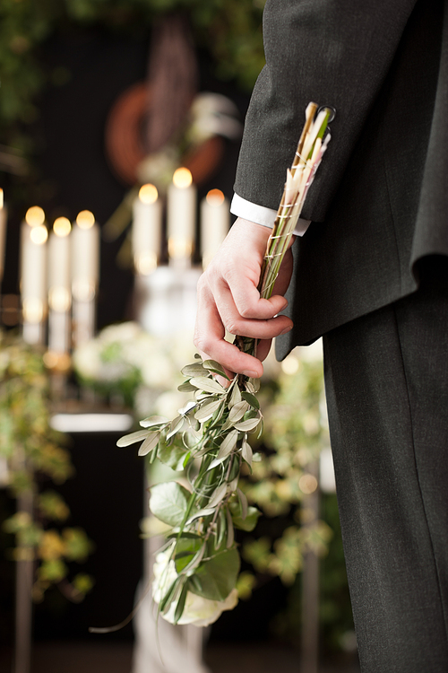 Religion, death and dolor  - man at funeral with white rose mourning the dead