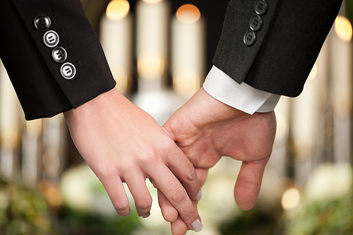 Religion, death and dolor  - couple at funeral holding hands consoling each other in view of the loss