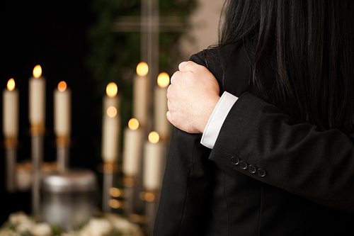 Religion, death and dolor  - couple at funeral consoling each other in view of the loss