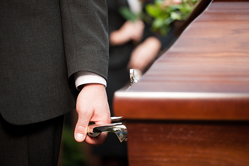 Religion, death and dolor  - coffin bearer carrying casket at funeral to cemetery