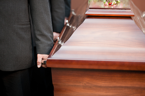 Religion, death and dolor  - coffin bearer carrying casket at funeral to cemetery