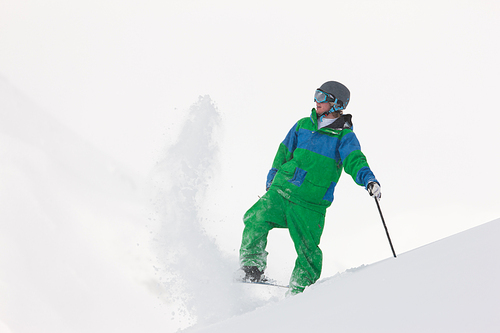 Skier dusting some snow in the alps in anticipation of his next downhill race