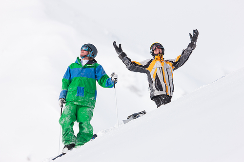 Skier and snowboarder in the snow looking into an alpine winter landscape in anticipation of the next downhill race