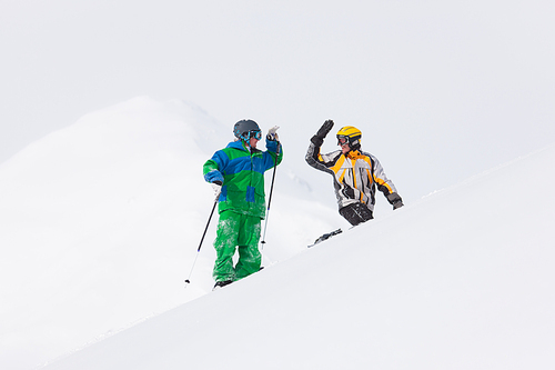 Skier and snowboarder in the snow giving five an alpine winter landscape in anticipation of the next downhill race