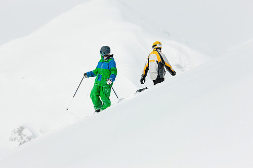 Skier and snowboarder in the snow giving five an alpine winter landscape in anticipation of the next downhill race