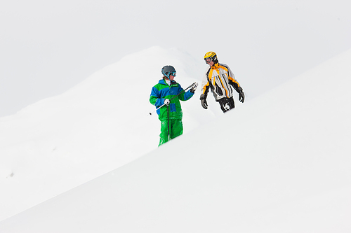 Skier and snowboarder in the snow looking into an alpine winter landscape in anticipation of the next downhill race