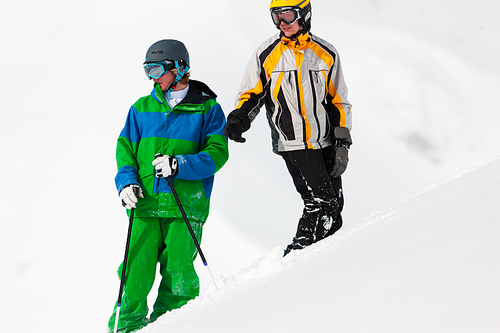 Skier and snowboarder in the snow looking into an alpine winter landscape in anticipation of the next downhill race