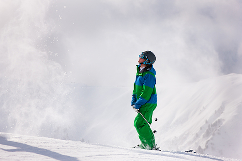 Skier dusting some snow in the alps in anticipation of his next downhill race