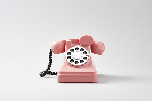 흰 배경 위에 있는 복고풍 분홍색 다이얼 전화기