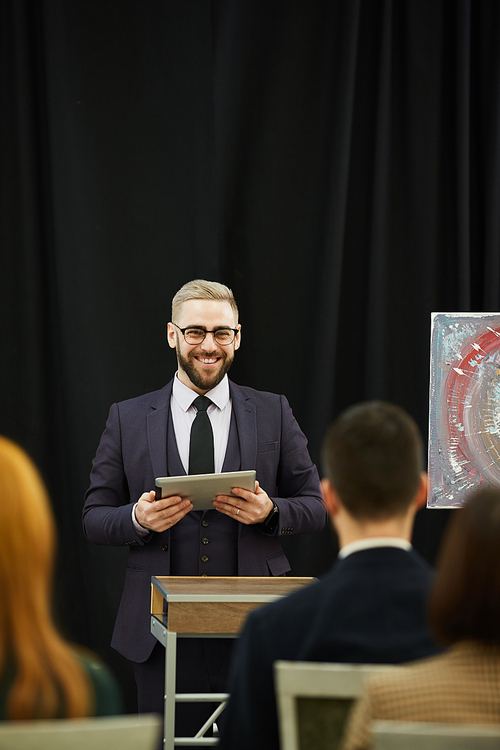 Successful young businessman in suit using digital tablet while holding the business presentation