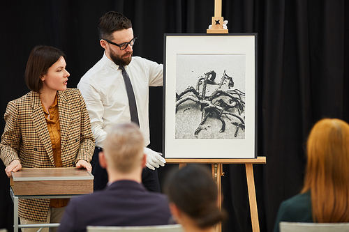 Businessman together with businesswoman presenting new painting to the business people during business presentation