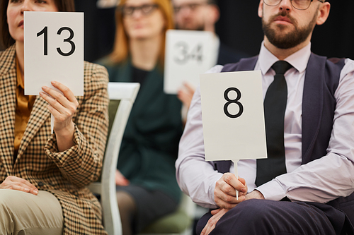 Group of business people holding signs with numbers while they sitting on auction