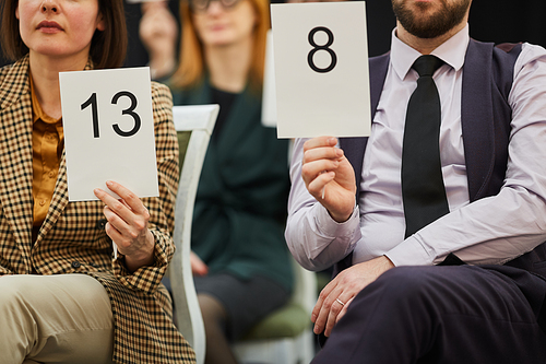 Close-up of business people sitting on chairs with signs with numbers and voting