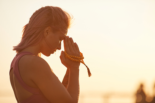 Young woman with short blond hair doing yoga and meditating during sunset on fresh air