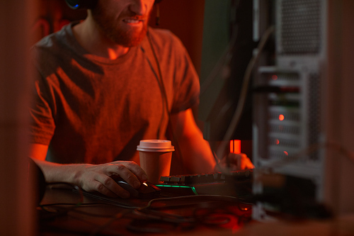 Close-up of computer programmer working till night and drinking coffee at his workplace at office