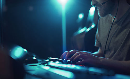 Close-up of computer programmer sitting at the table and typing on computer keyboard he working in dark office