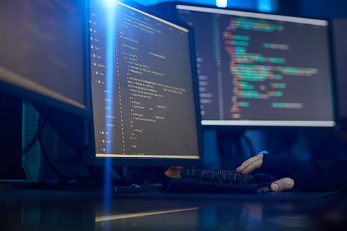 Image of computer monitors with software standing on the table in dark office