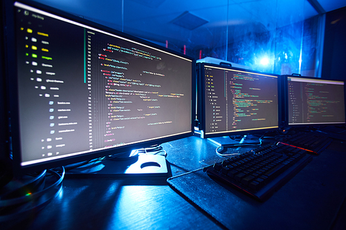 Image of computer monitors updating the software they standing on the table in dark room