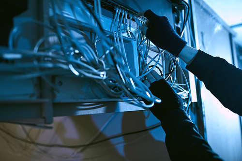 Close-up of gangster in black gloves holding wires and turning off the electricity before the crime