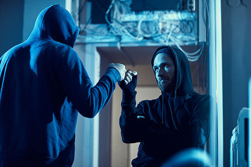 Two computer hackers giving a high-five to each other they finished their criminal deal successfully in dark office