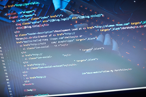 Close-up of man typing computer codes and reading them on computer monitor