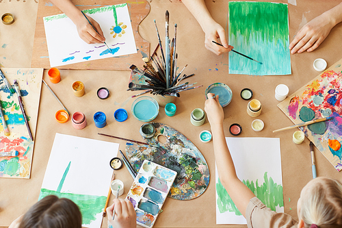 High angle view of group of children painting their pictures with watercolor paints during art lesson