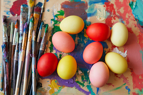 Close-up of colored Easter eggs lying on the painting with paintbrushes ready to Easter holiday