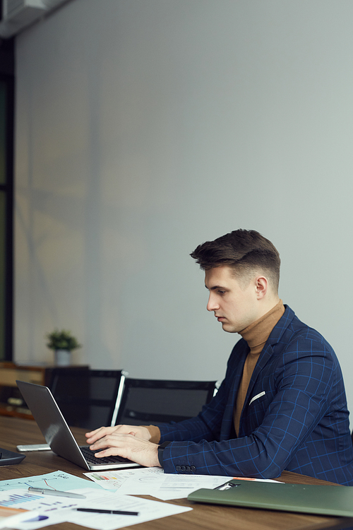 Young office worker sitting at the table and typing on laptop computer he working online at office