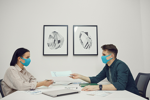 Young business people wearing protective masks discussing working moments together at the table during a meeting at office